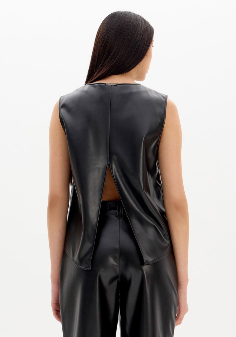 Visão full body frontal: modelo veste blusa sem mangas preta com decote V e calça preta reta em PU, look urbano com scarpin de salto