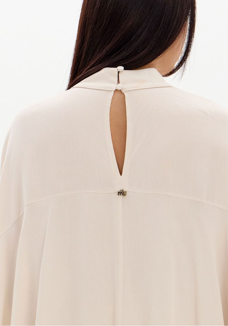 Verso da blusa bata bege com abertura em gota e botão na nuca, camadas de babados sobrepostas