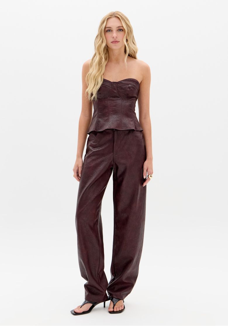 Close-up frontal da blusa corset vinho em PU em modelo loira, destacando recortes do bojo e textura do material