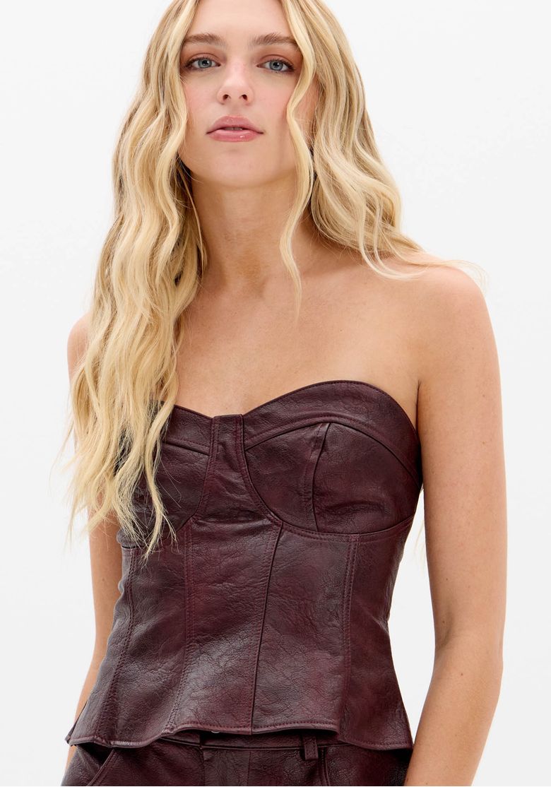 Modelo loira em pose de corpo inteiro vestindo blusa corset sem alça vinho em PU e calça larga combinando, visual completo para eventos noturnos