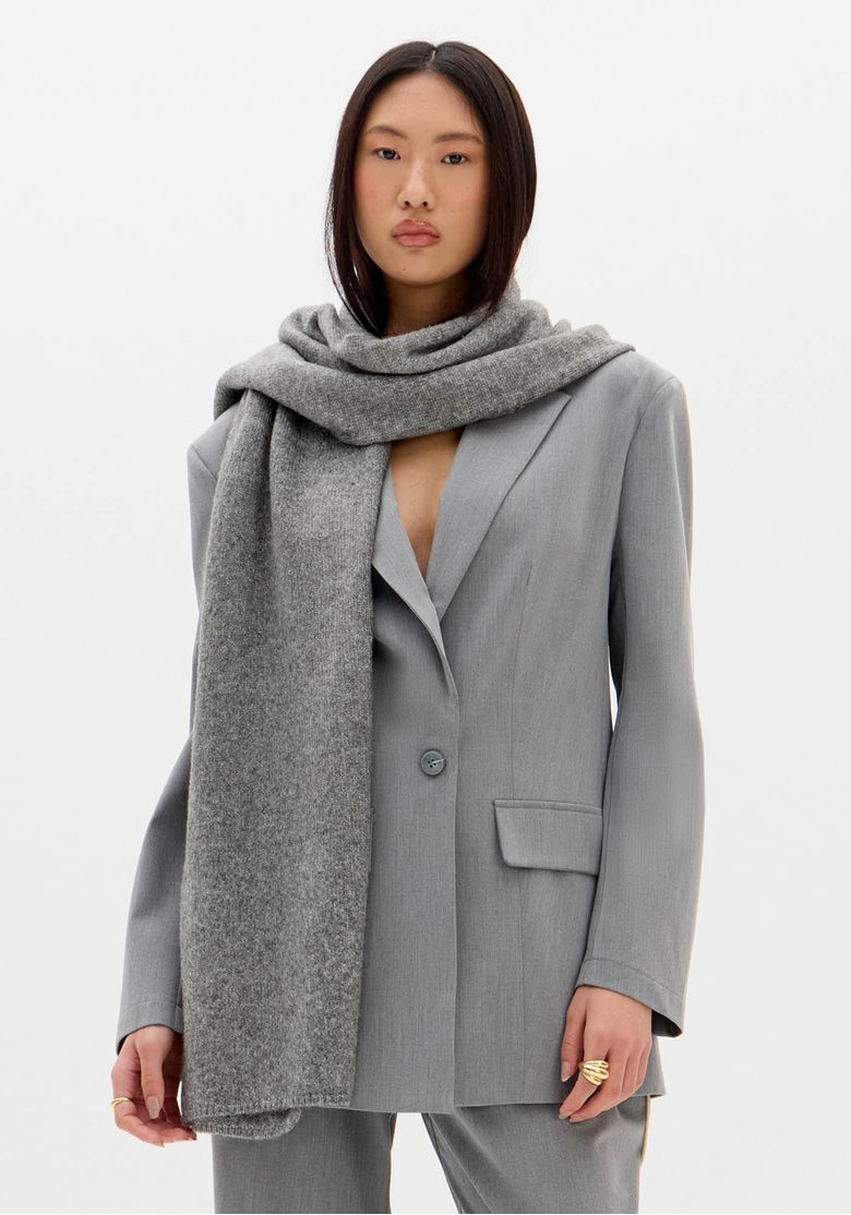 Modelo vestindo blazer oversized cinza com cachecol, mostrando o visual frontal.