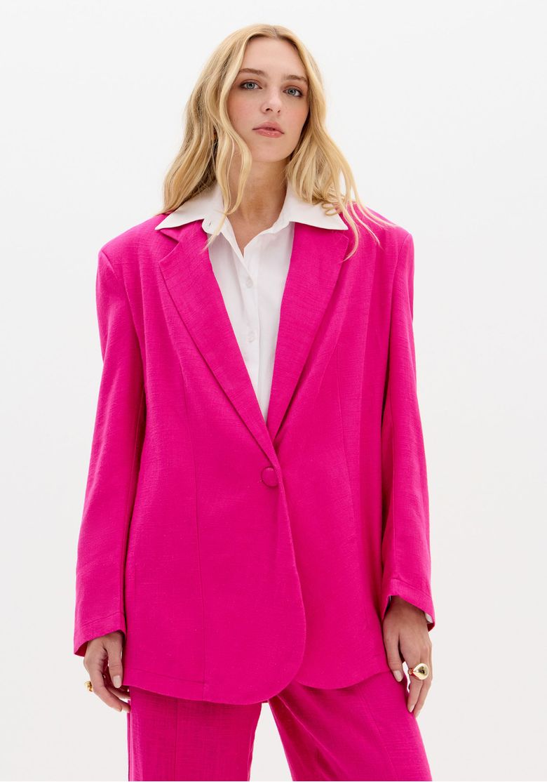 Modelo vestindo blazer oversized rosa com lapela clássica e botão único, vista frontal.