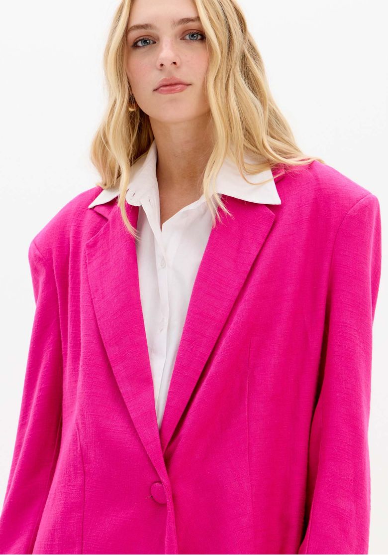 Detalhe do blazer rosa mostrando a lapela clássica e o botão único.
