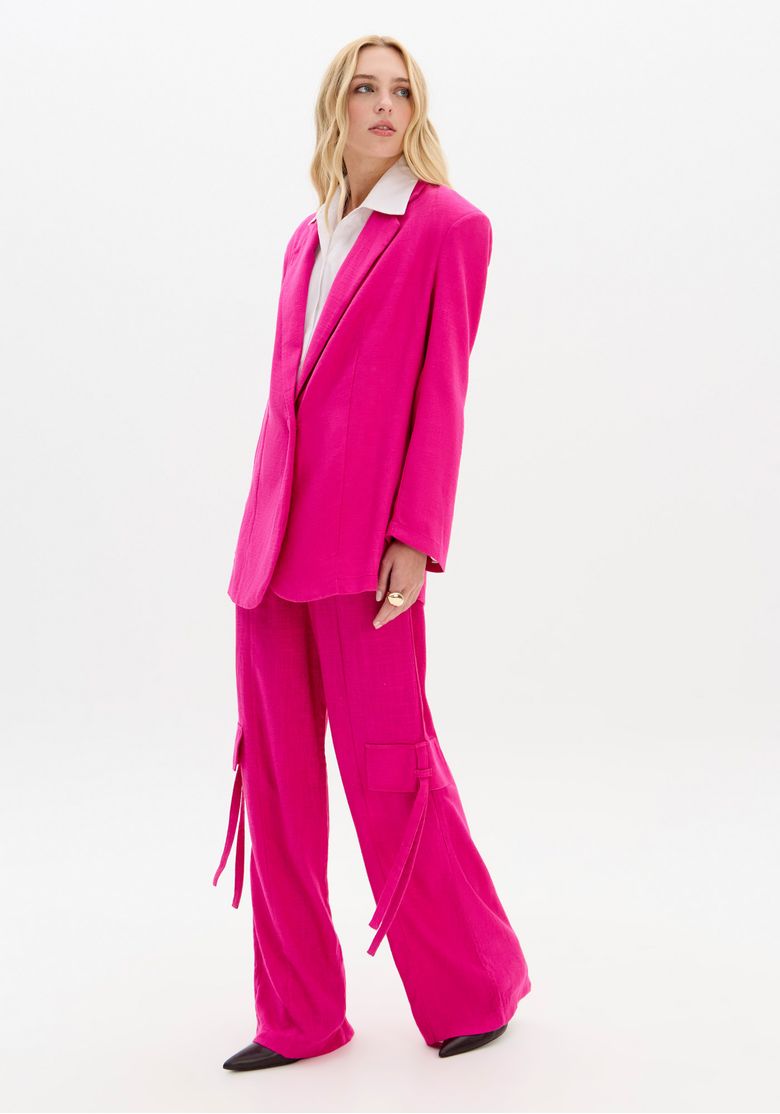 Vista lateral do blazer rosa oversized, destacando o caimento alongado.