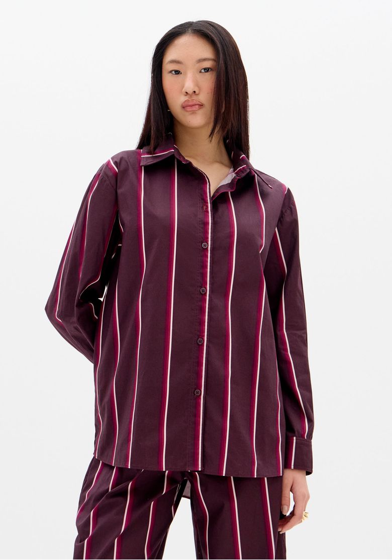 Costas-da-camisa-listrada-vinho-com-pala-prega-central-e-barra-arredondada-em-tecido-plano-leve