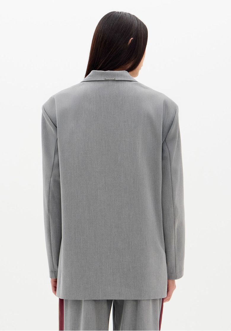 Vista traseira do blazer oversized cinza, destacando o corte alongado.