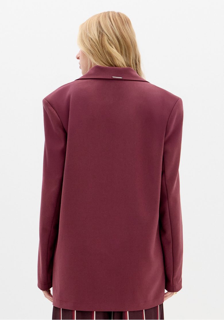 Vista frontal em fundo branco do blazer feminino vermelho oversized, mostrando lapela clássica, fechamento em um botão e bolsos com aba