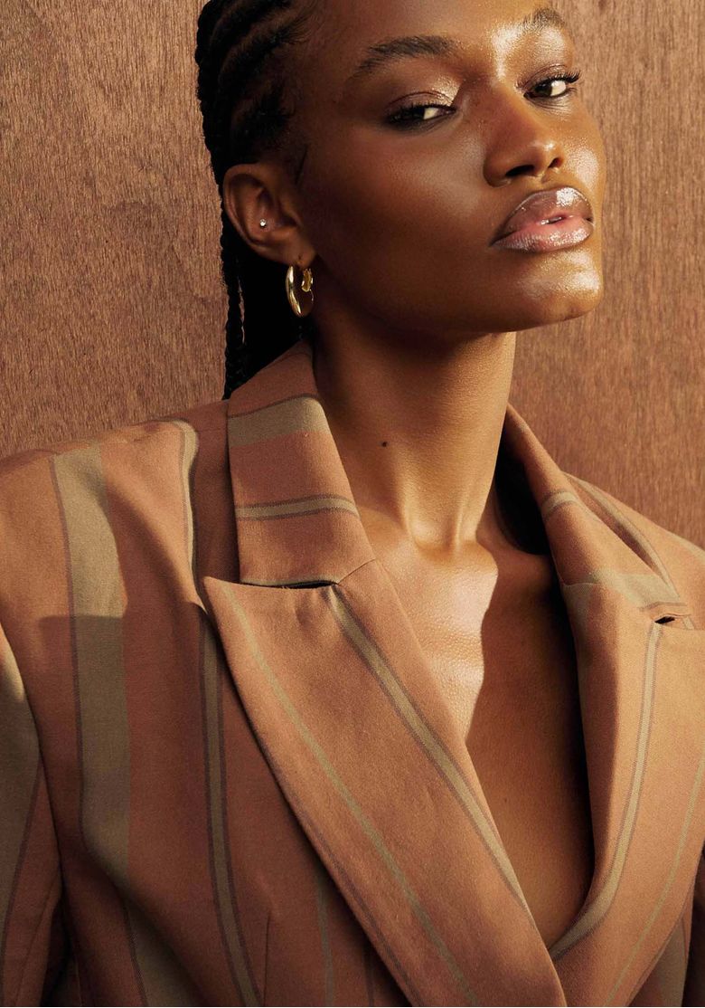 Look completo em estúdio com blazer e calça listrada marrom, caimento amplo e perna larga ideal para ambiente de trabalho