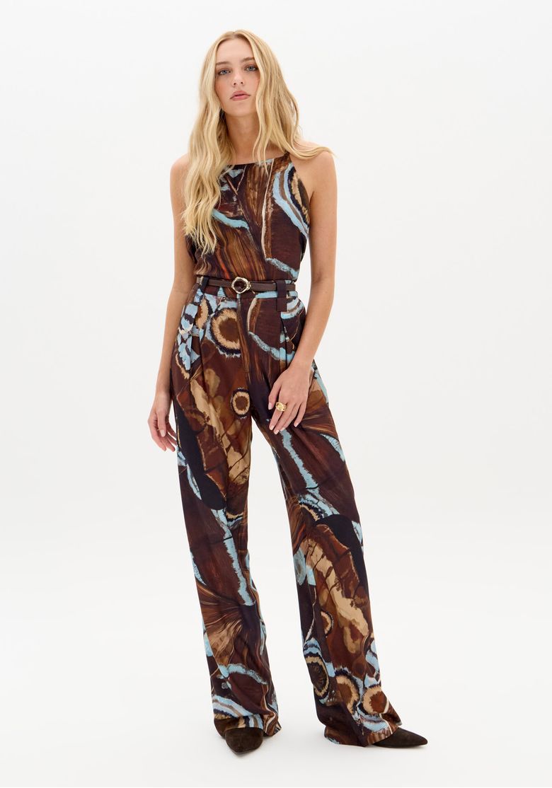 Modelo usando calça reta estampada marrom em viscose vista frontal completa com cinto de passantes e caimento fluido