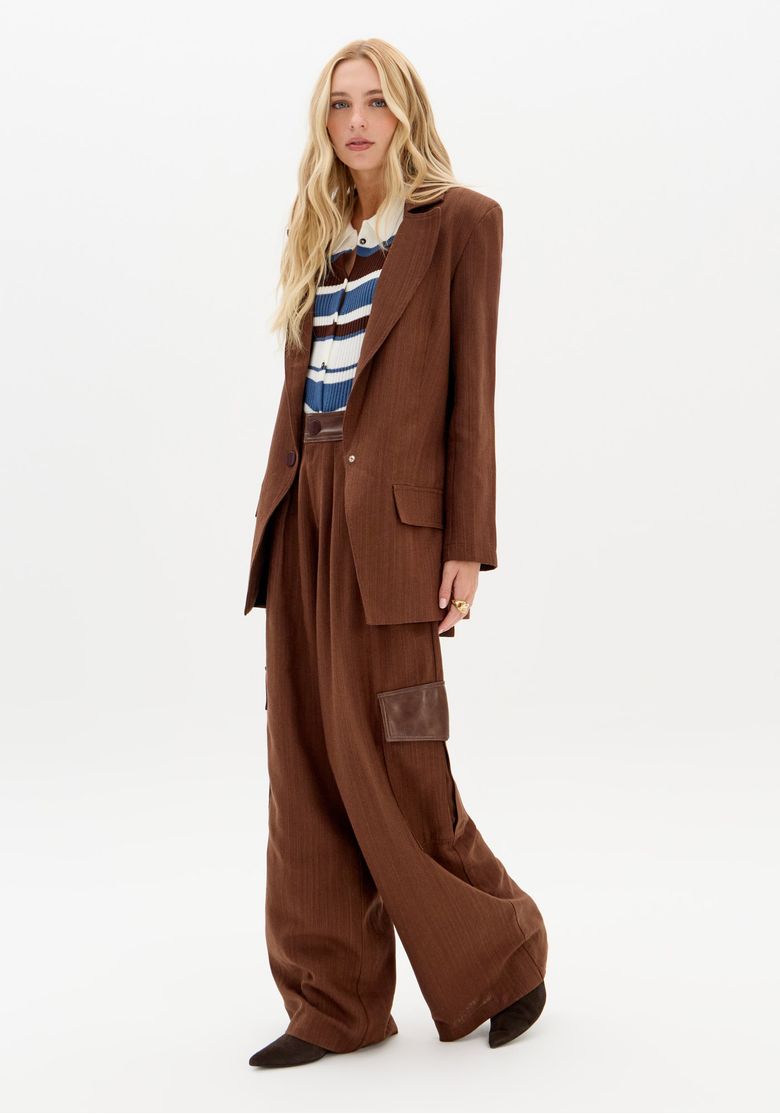 Modelo vestindo calça wide leg marrom com blazer combinando, em pose frontal.