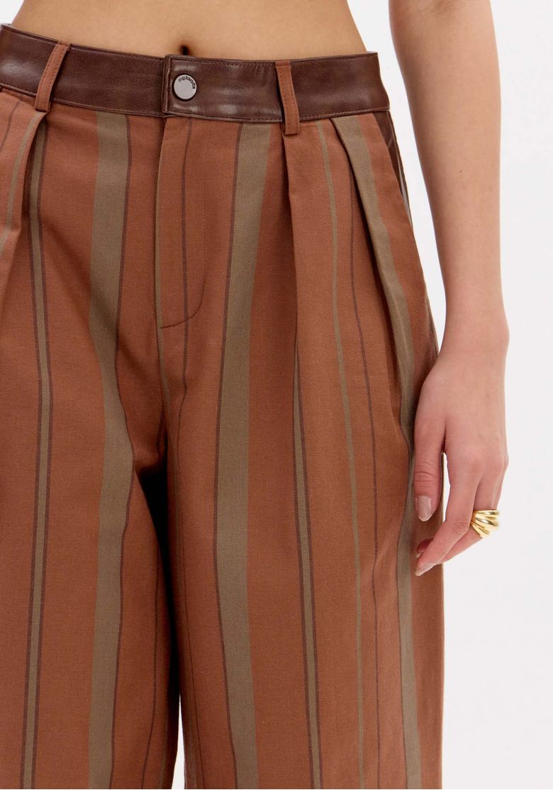 Detalhe traseiro da cintura da calça com cós em contraste e passantes, evidenciando acabamento e listras verticais