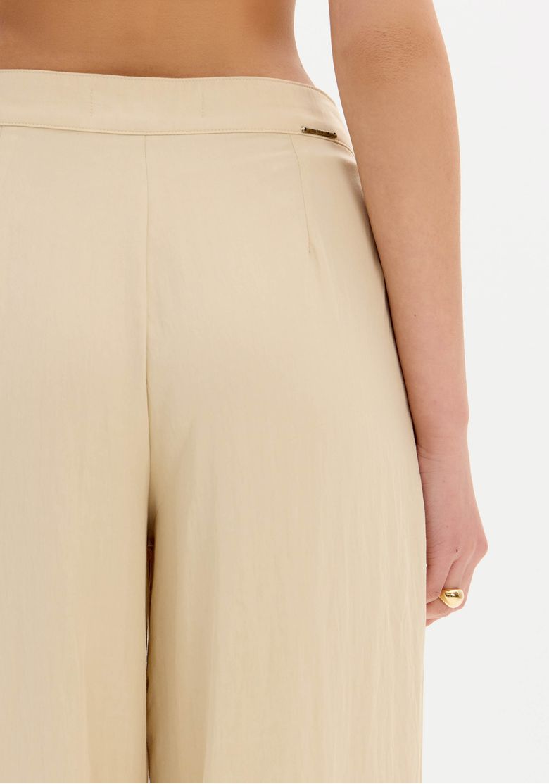 Detalhe do cós traseiro da calça slouchy bege mostrando acabamento limpo e ausência de bolsos aparentes