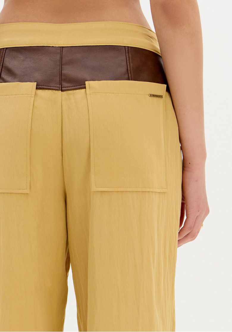 Vista lateral da calça wide leg bicolor mostrando o caimento solto e elegante.