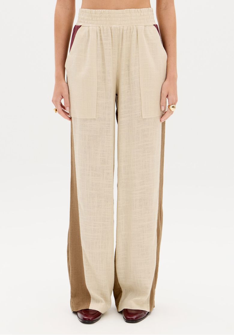 Vista frontal completa da calça reta bicolor com bolsos chapados, perna longa e caimento fluído