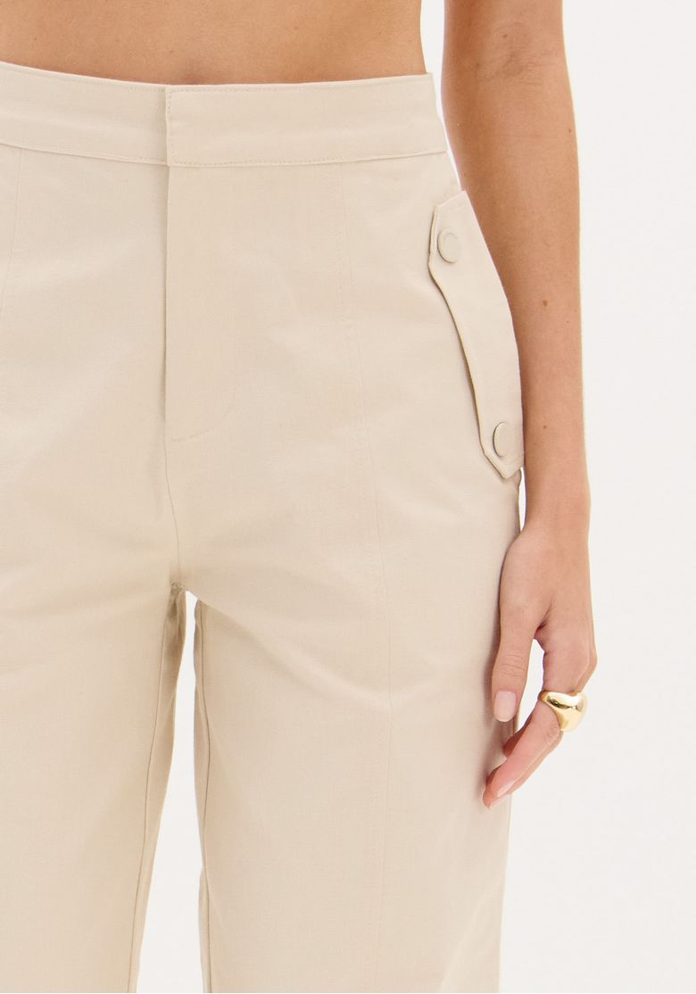 Visão traseira da calça full length bege mostrando o cós limpo e o caimento reto até a barra
