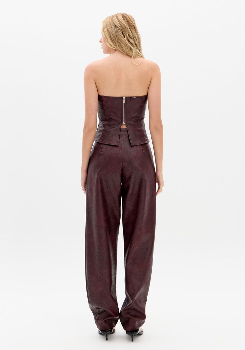 Calça barrel vinho vista frontal em modelo feminino, perna larga e fechamento frontal por zíper e botão.
