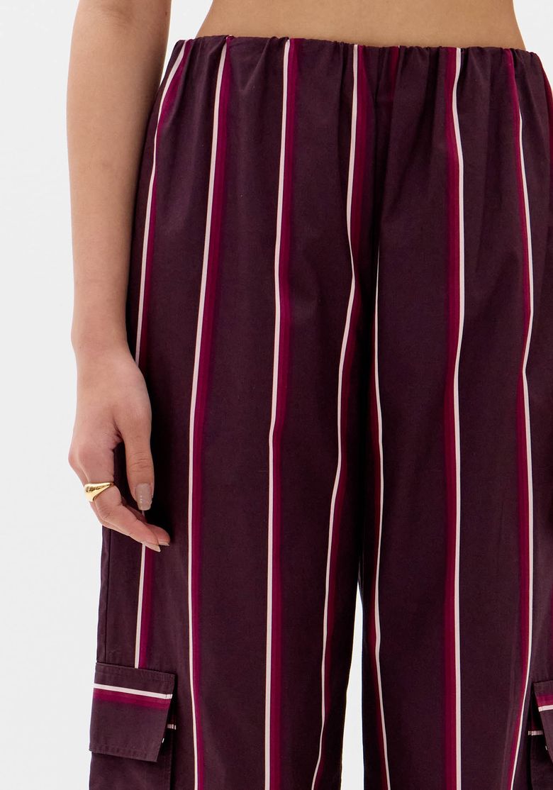 Modelo de costas vestindo a calça wide leg listrada com top vermelho.