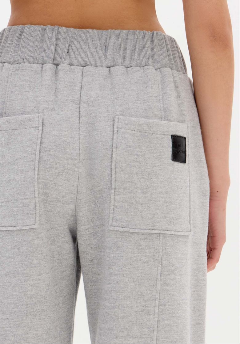 Close do bolso traseiro com etiqueta preta na calça de moletom cinza, detalhe do acabamento