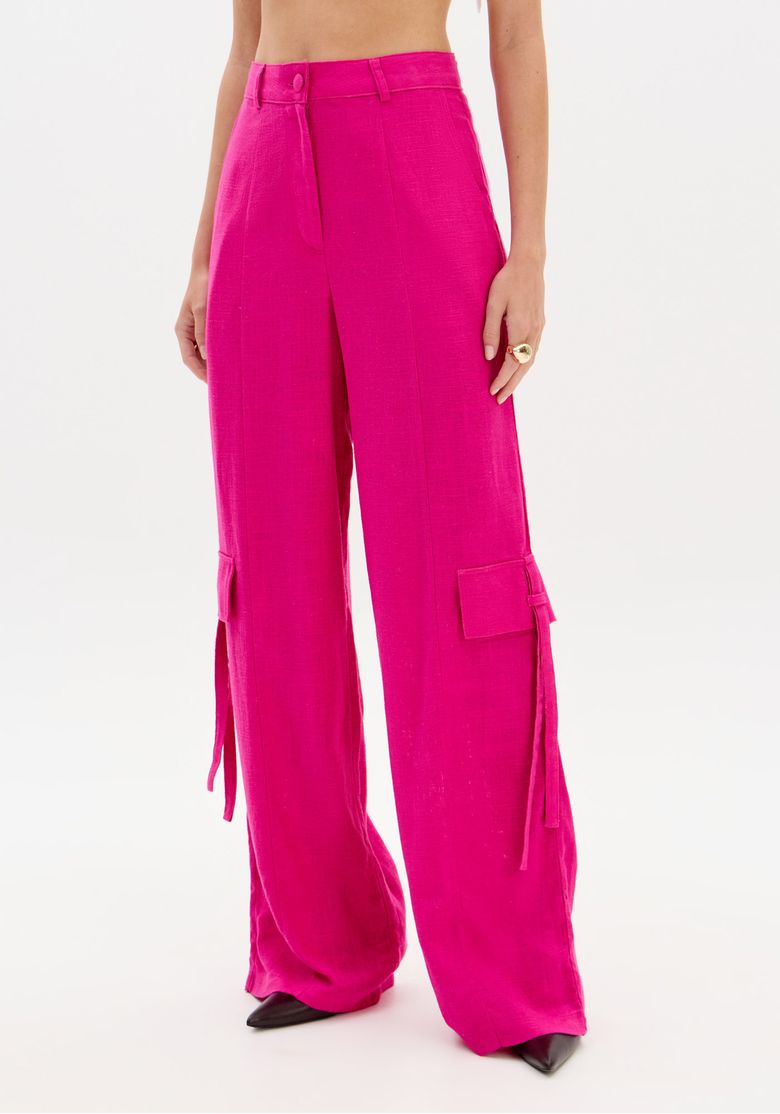 Vista frontal da calça rosa com perna larga, destacando bolso utilitário lateral com aba e tiras aplicadas
