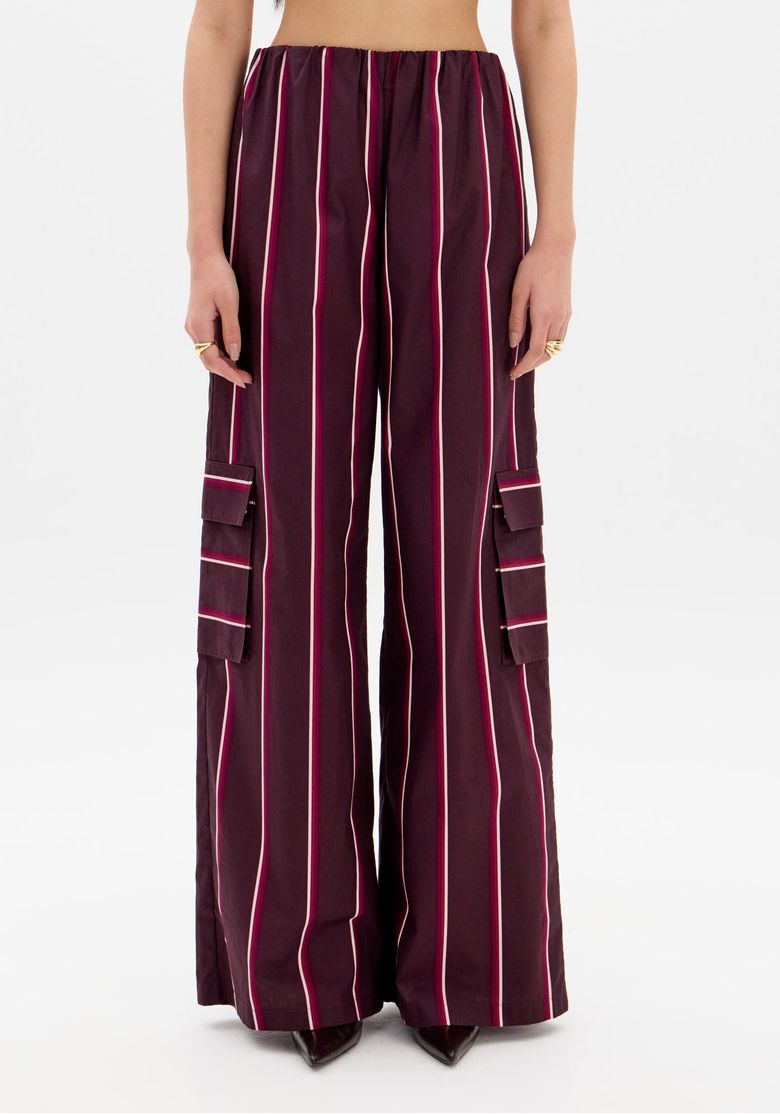 Modelo vestindo a calça wide leg listrada com top vermelho.