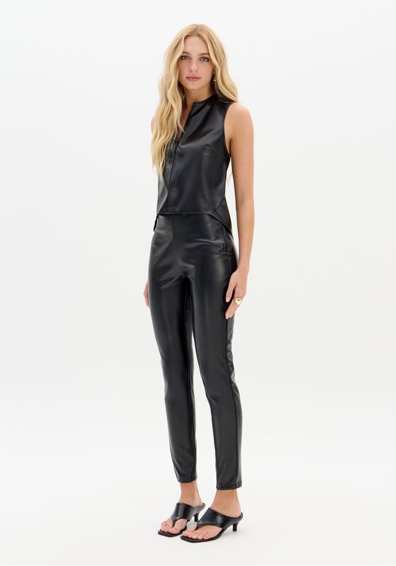 Modelo vestindo calça legging preta com acabamento acetinado, vista frontal.