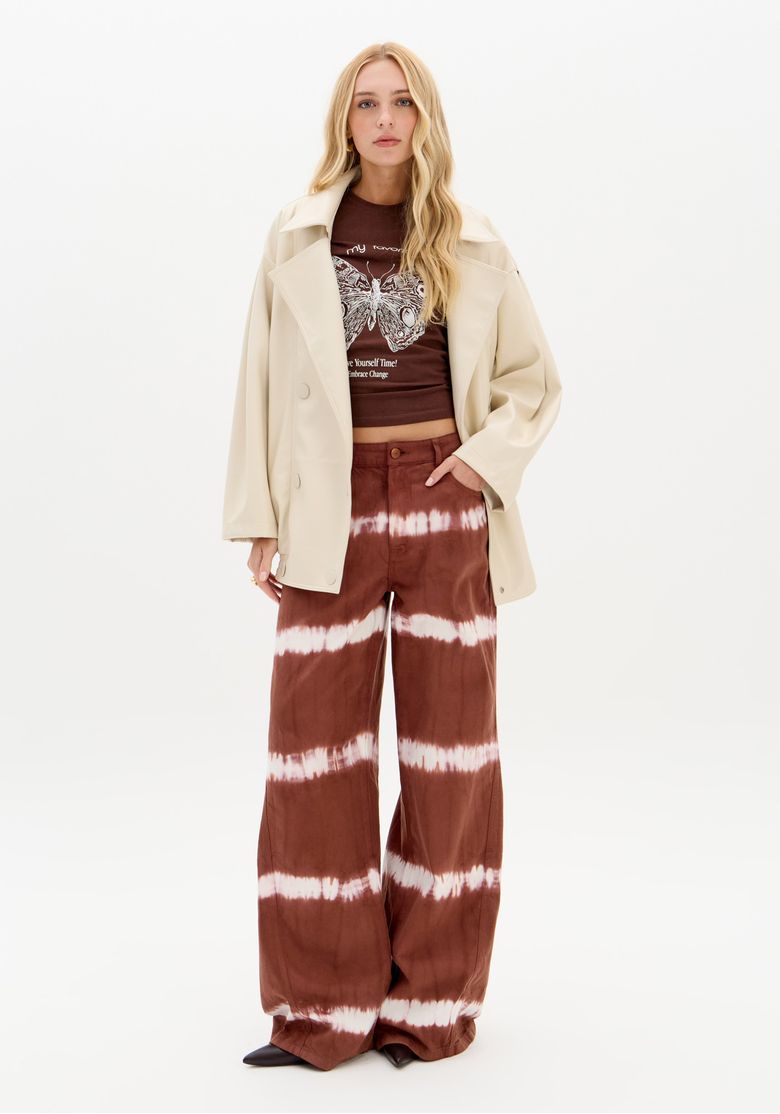 Modelo vestindo jaqueta oversized bege com calça estampada, mostrando o visual completo.