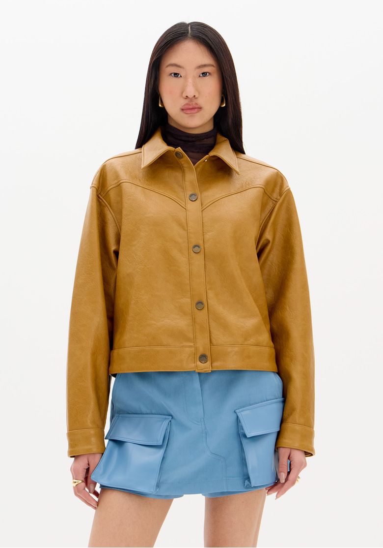 Visao-de-corpo-inteiro-em-estudio--jaqueta-biker-bege-cropped-em-PU-combinada-com-saia-azul-de-bolsos-e-botas-marrom-cano-medio