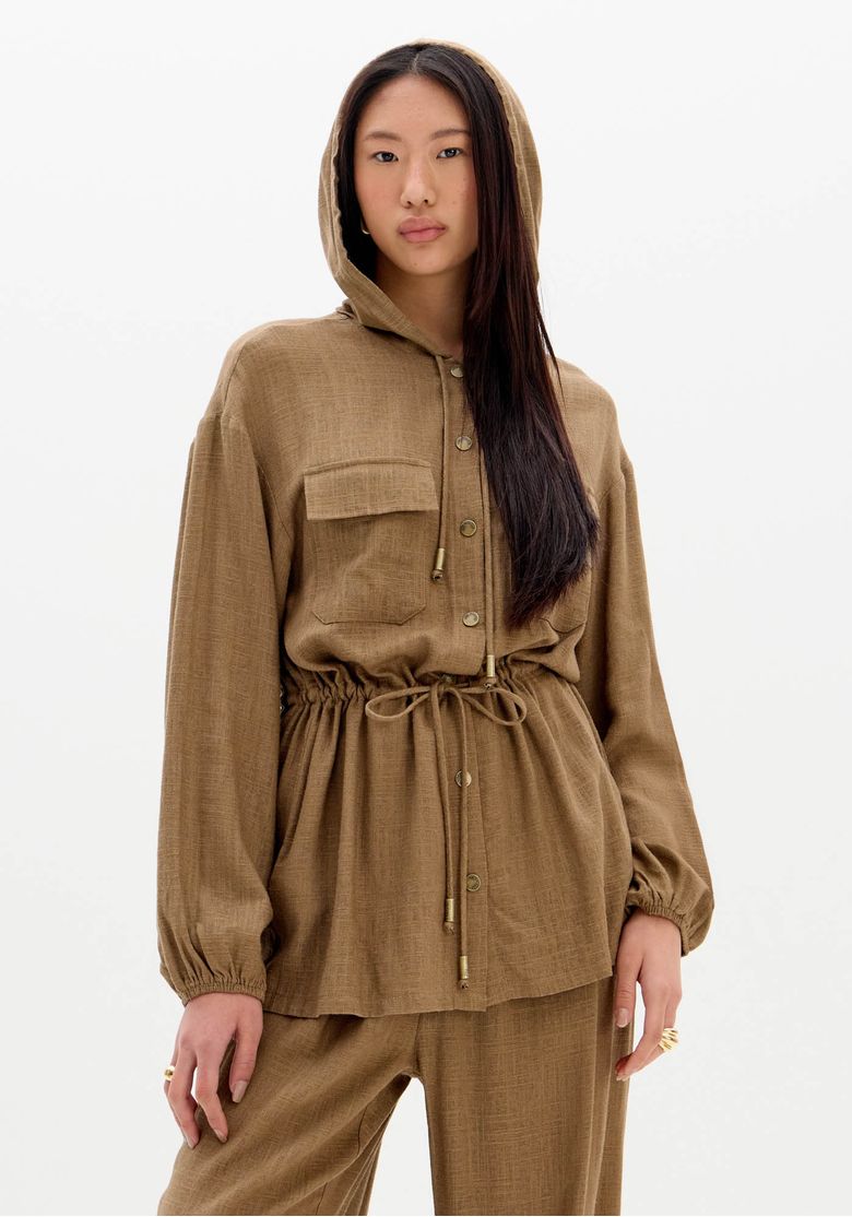 Modelo vestindo parka feminina alongada com capuz, na cor marrom, vista lateral.