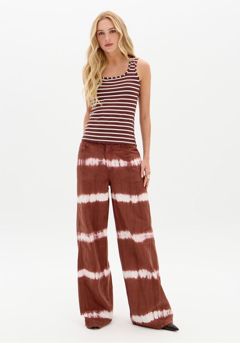 Visao-frontal-de-corpo-inteiro-com-regata-listrada-canelada-combinada-com-calca-pantalona-tie-dye-look-casual-e-moderno