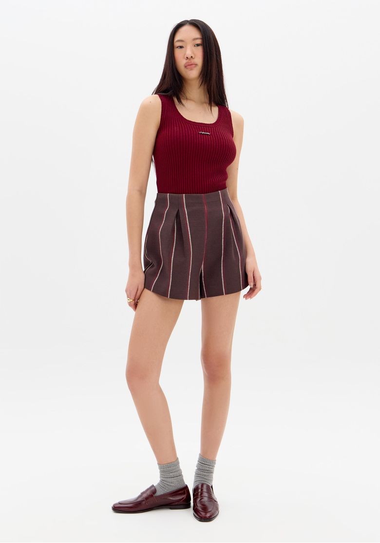 Modelo em pé usando short evasê listrado marrom de cintura alta e regata vinho, vista frontal completa