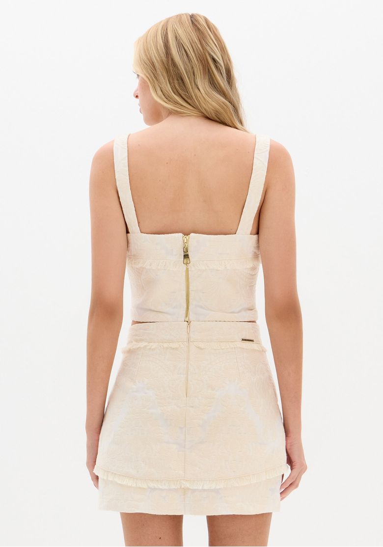 Close-up of the beige crop top with paisley embroidery, highlighting the fabric texture and hem detail