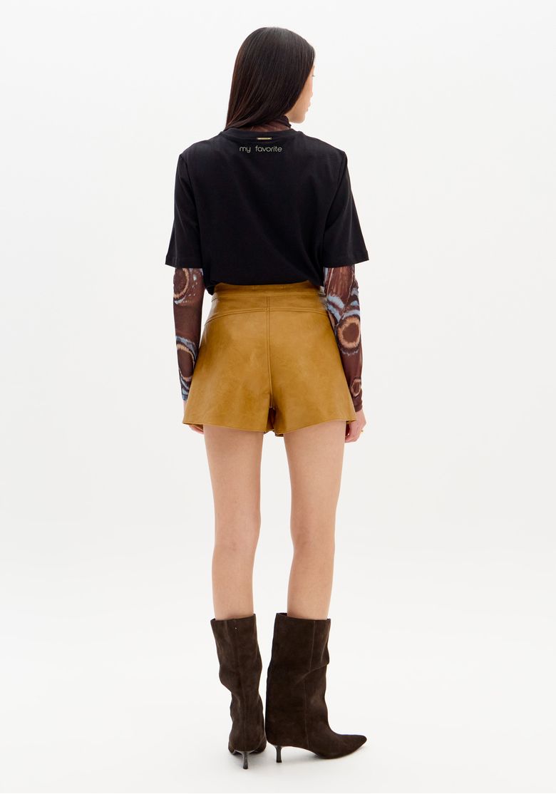 Vista-posterior-do-short-saia-PU-bege-em-modelo-ressaltando-o-corte-de-shorts-por-baixo-e-o-cos-medio.