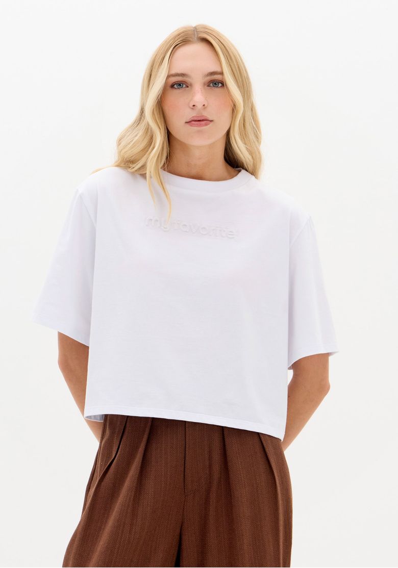 Modelo usando camiseta oversized branca em malha leve 100% algodão, vista frontal com comprimento médio e caimento solto