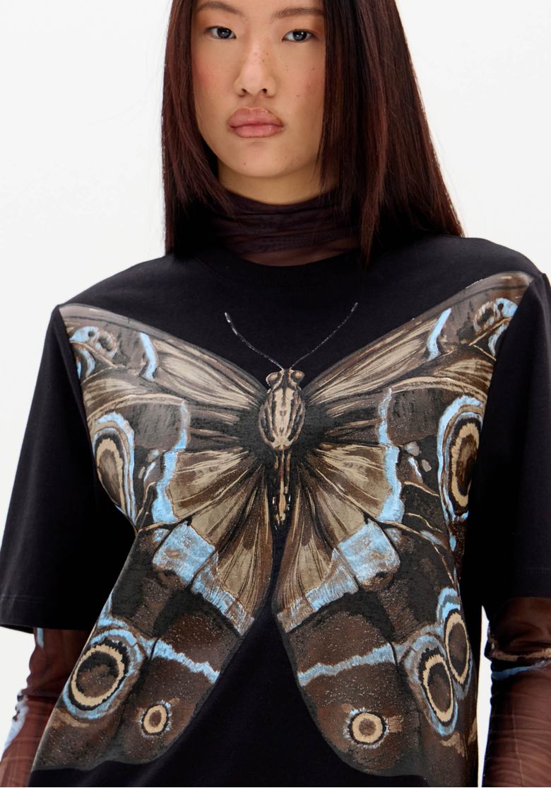 Detalhe da estampa de borboleta na t-shirt oversized preta.