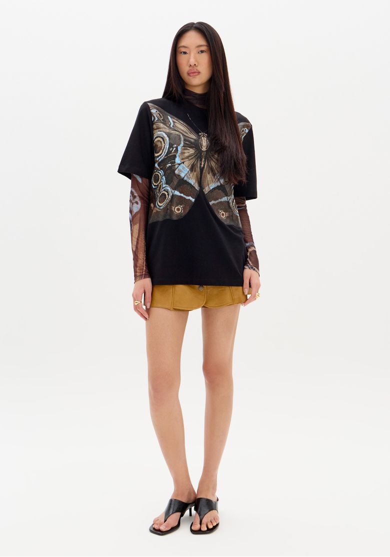Vista lateral da t-shirt oversized preta com estampa de borboleta.