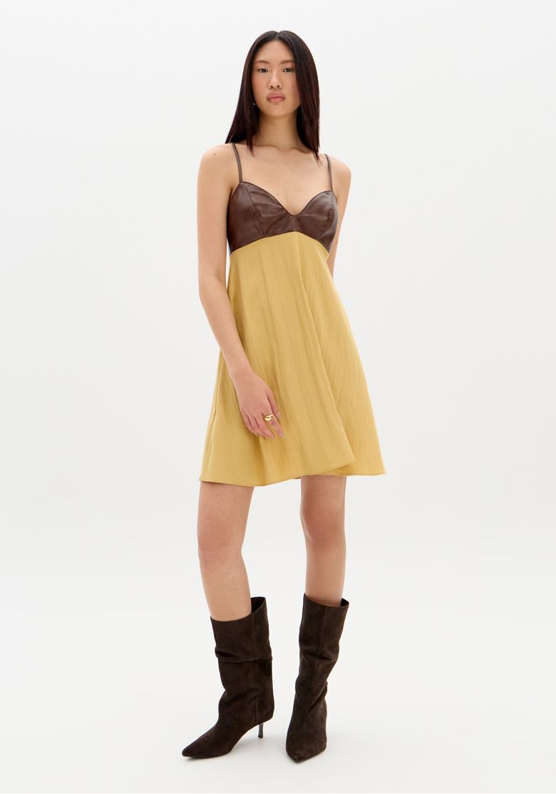 Modelo de frente vestindo vestido curto bege com alças finas e busto estruturado em PU, look casual urbano