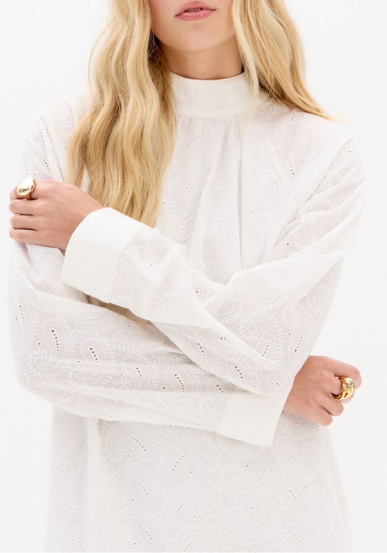 Detalhe do decote alto e punho do vestido laise branco com acabamento em tecido plano leve