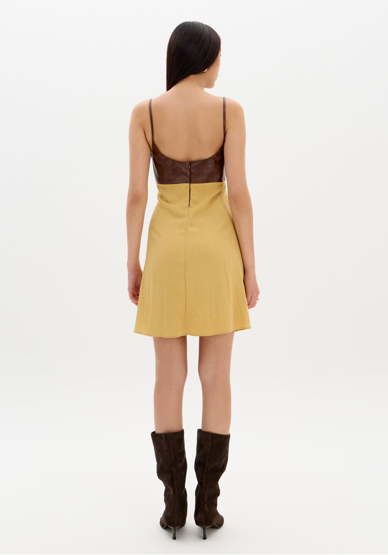 Close frontal do busto estruturado em PU do vestido curto bege com alças finas e detalhe do decote