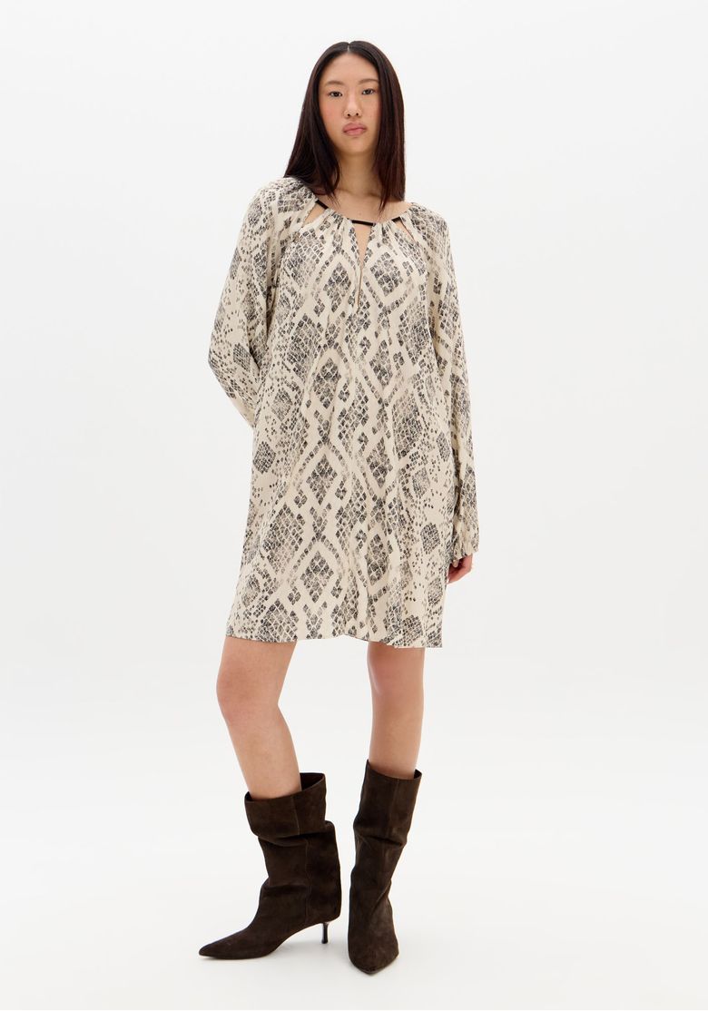 Modelo vestindo vestido curto estampado bege em viscose, vista frontal completa com mangas longas e botas marrons, look casual urbano