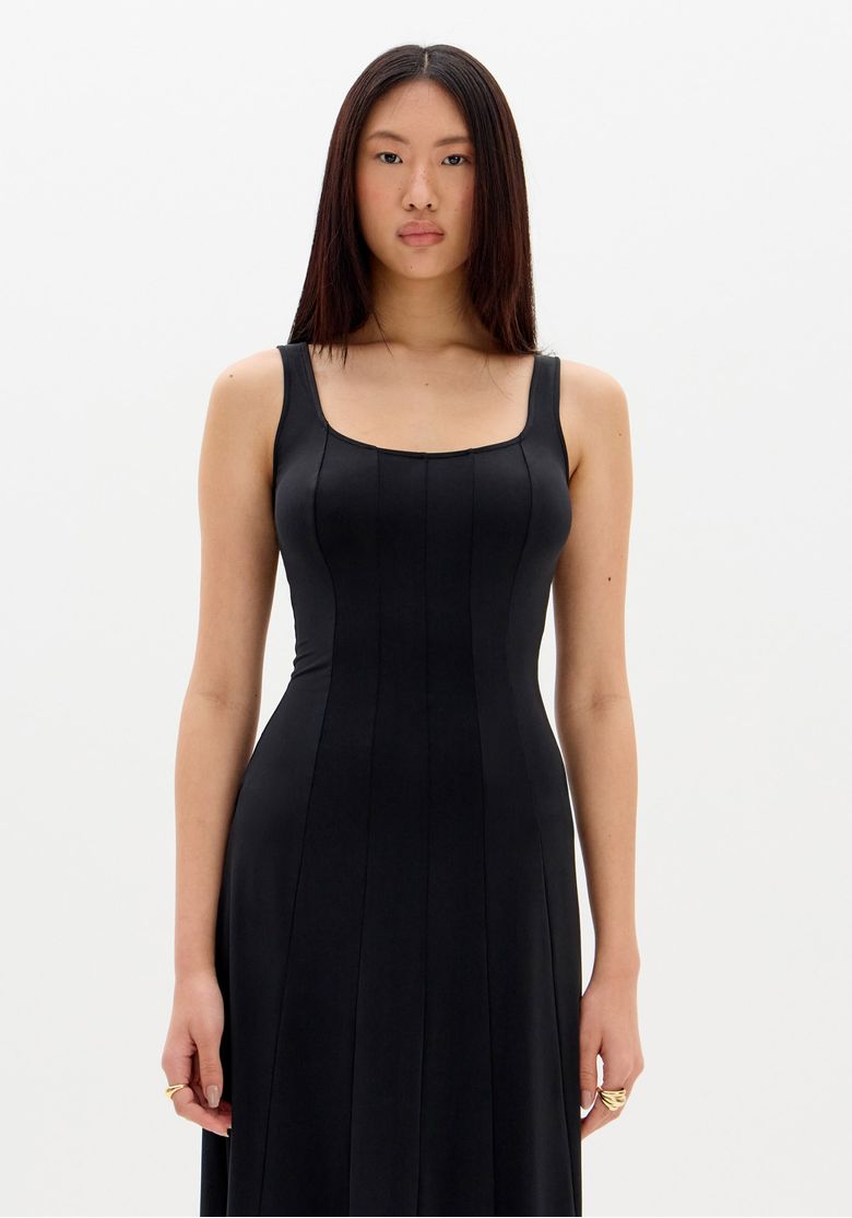 Vista traseira do vestido super midi preto mostrando as nesgas e o caimento fluido da barra reta