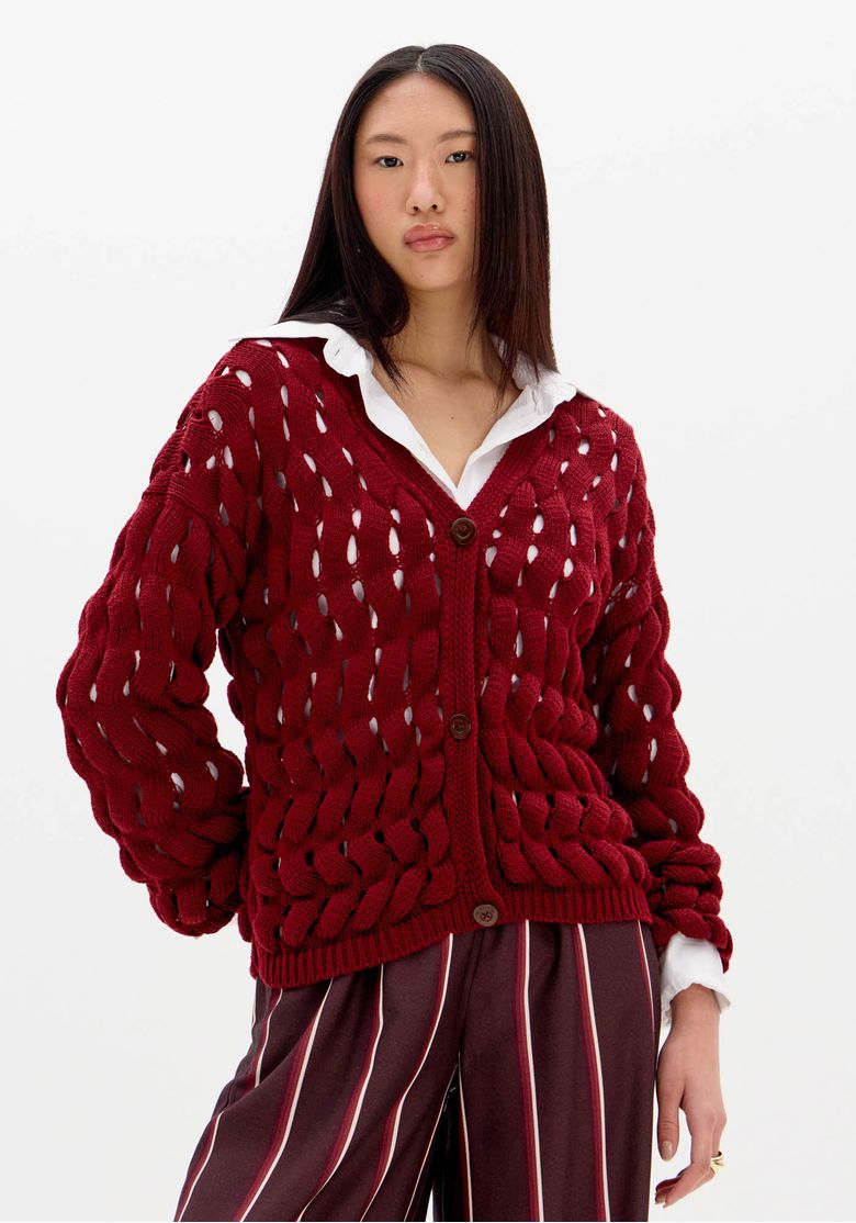 Cardigã feminino em tricô vazado vermelho com mangas longas e botões frontais, visto de frente.
