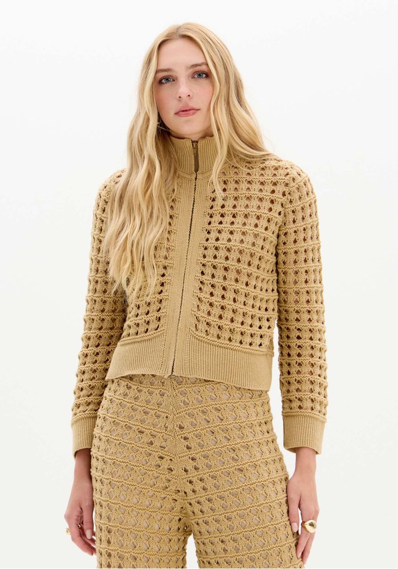 Modelo em pé usando jaqueta tricô bege gola alta com zíper frontal e calça tricot coordenada, vista frontal completa - jaqueta tricô bege casual urbano
