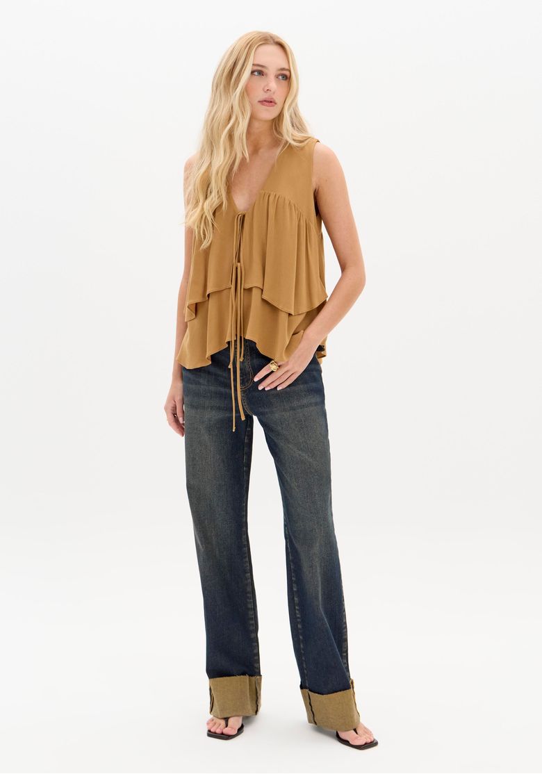 Modelo vestindo a blusa ampla bege com calça jeans.