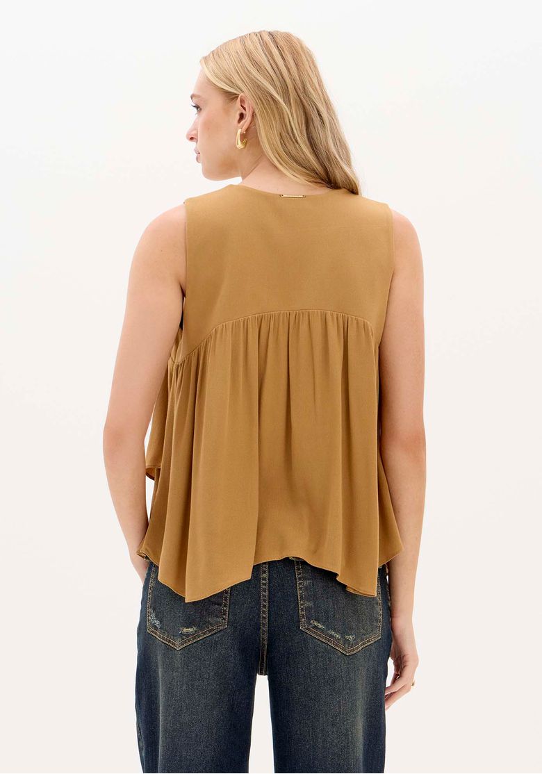 Vista traseira da blusa ampla bege mostrando o caimento fluido.