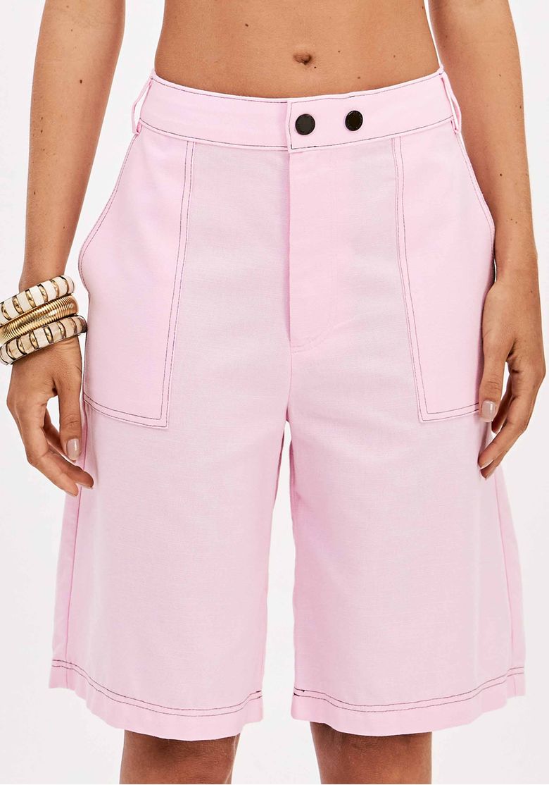 Detalhe do cós com passantes e bolsos frontais da bermuda rosa.