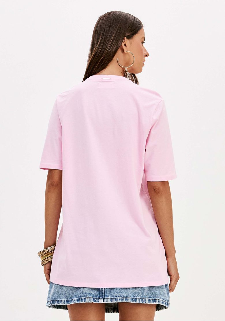 Vista lateral da t-shirt oversized rosa, destacando o comprimento alongado.