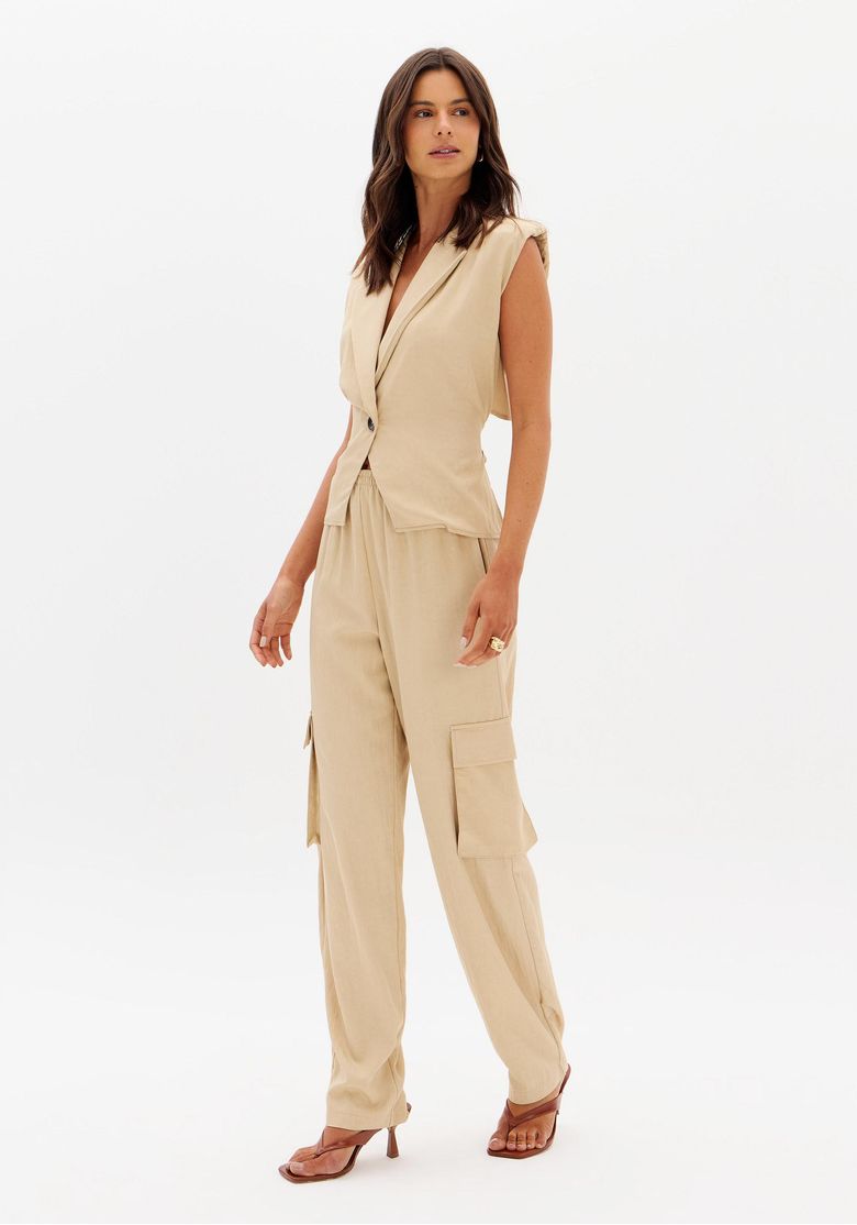 Modelo vestindo calça relaxed utilitária marrom vista frontal 3/4 com top sem mangas, destacando bolsos cargo e cós elástico