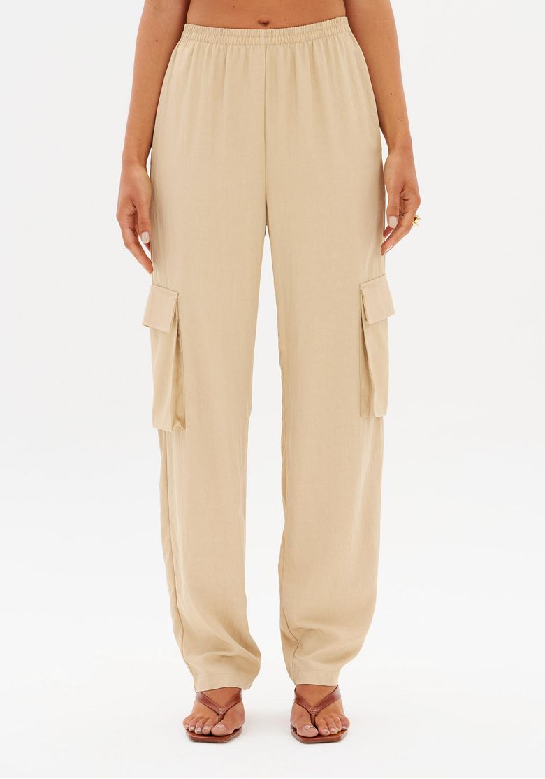 Vista traseira da calça utilitária marrom mostrando cós elástico e bolsos laterais com aba, look completo com top amarrado nas costas