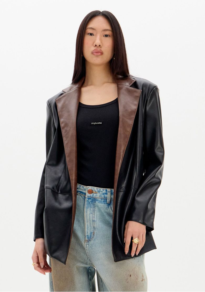 Modelo-usando-regata-canelada-preta-sob-blazer-preto-com-pala-marrom-e-jeans-claro-look-de-sobreposicao-casual---regata-com-blazer-e-jeans