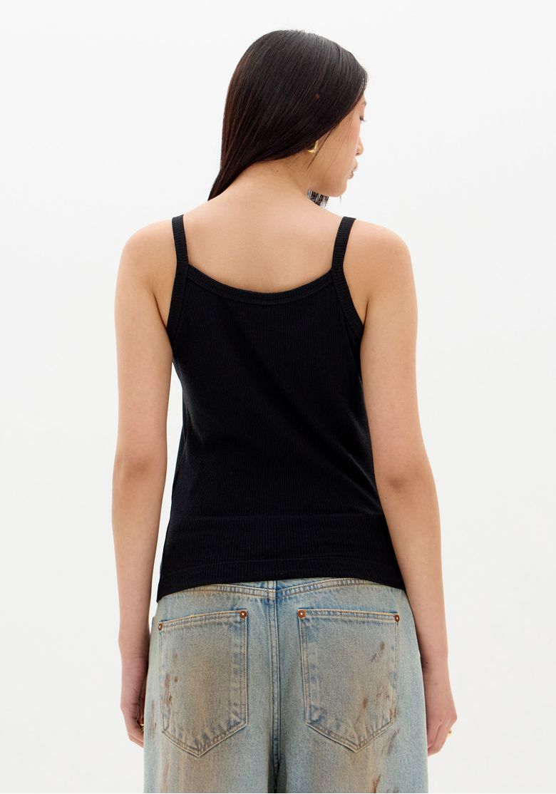 Vista-frontal-integral-da-regata-canelada-preta-de-alcas-finas-em-look-casual-com-jeans-claro-modelo-com-maos-no-bolso
